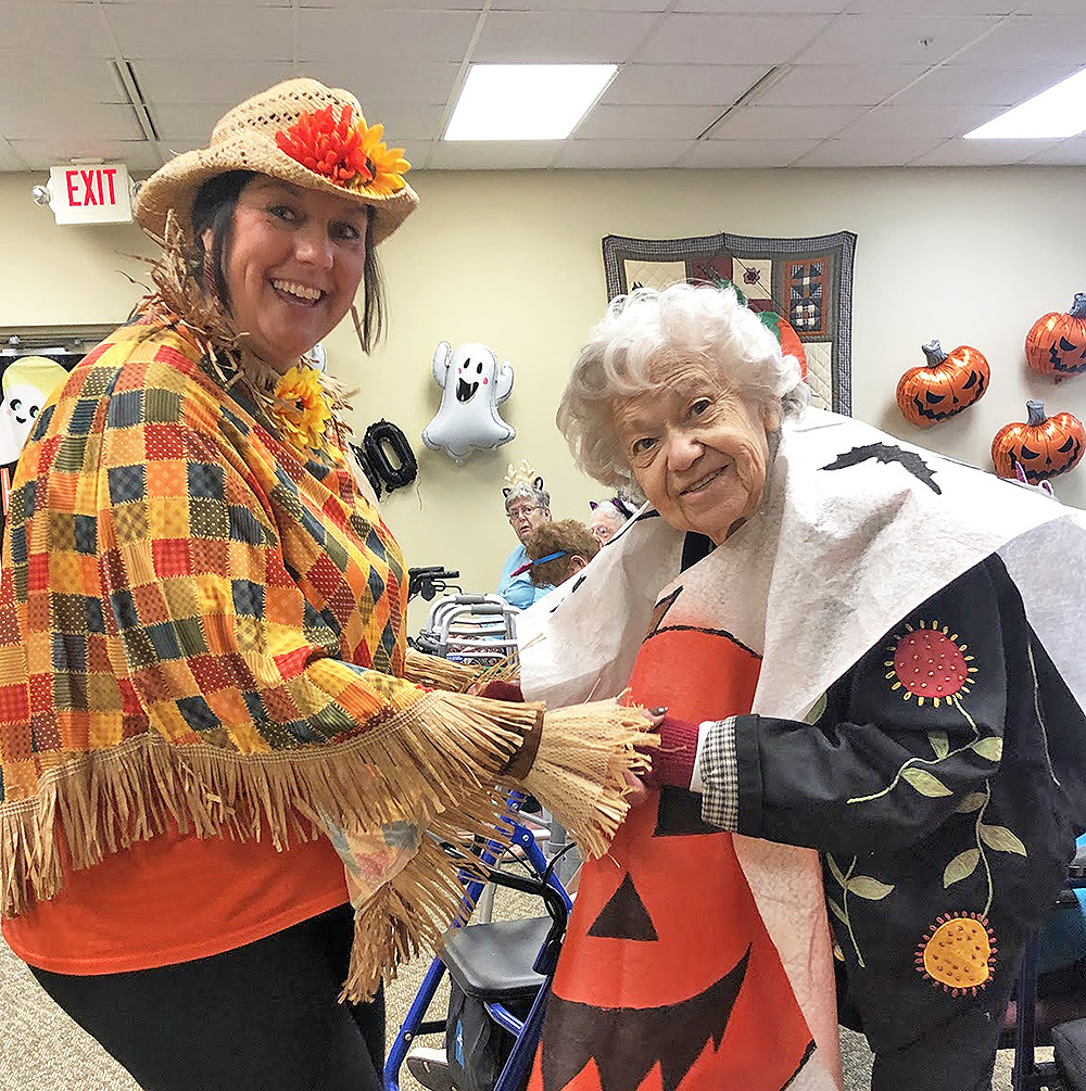 Assisted living resident and staff member dancing at Halloween party